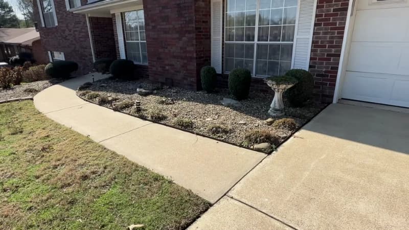 Cleaned concrete walkway and driveway apron beside a brick building