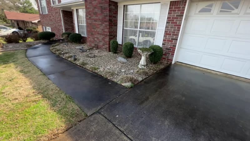 Driveway apron and walkway outside a garage, heavily soiled before pressure washing