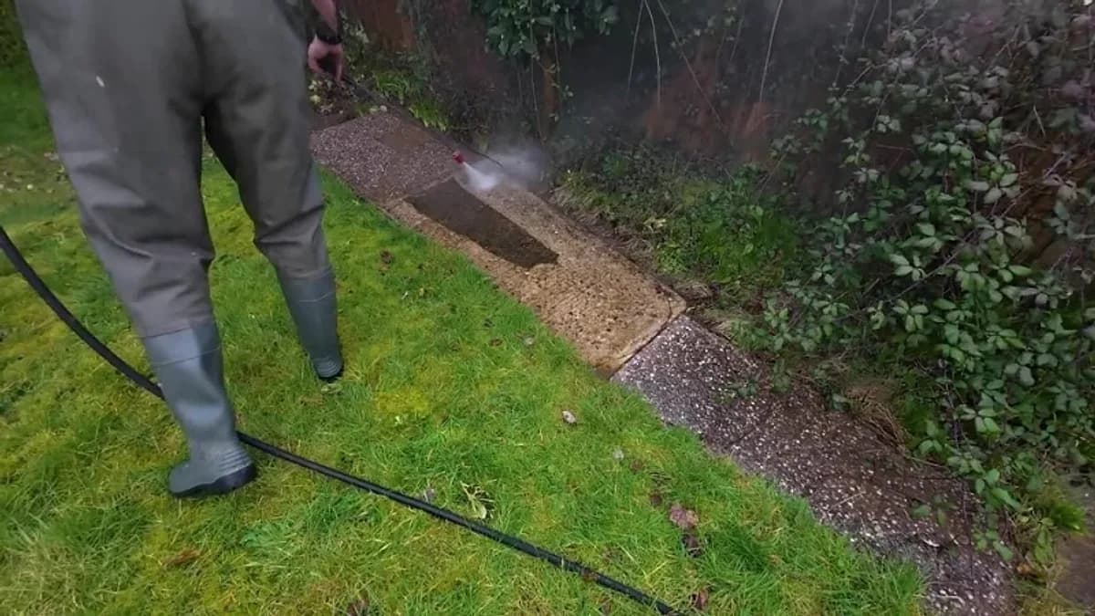Technician pressure washing a concrete path edge beside a lawn in Jacksonville, Florida