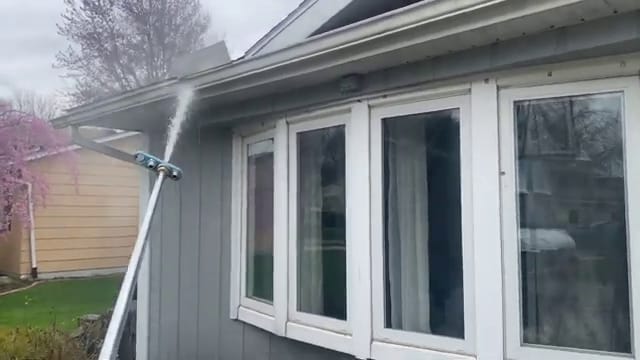 Pole-fed spray reaching the upper siding and gutter line of a home from the ground