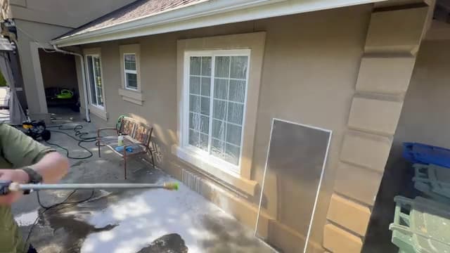 Cleaned window screen propped against a stucco wall after rinsing